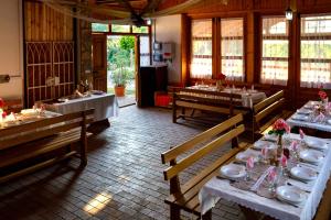 a dining room with tables and chairs and windows at Rózsa-Domb Vendégház in Golop