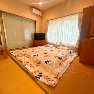 a large bed in a room with a large window at ペンション波 in Ufugumui