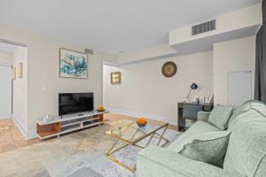 a living room with a couch and a tv at Classy 1-Bedroom & Den Condo in Heart of Downtown in Toronto