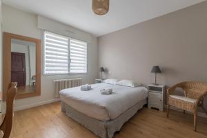 a bedroom with a bed and a window and a chair at L'AUTHENTIQUE - 600m plage - Piscine in Saint-Nazaire