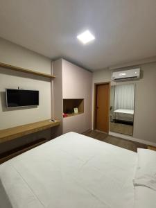 Un dormitorio con una gran cama blanca y un televisor. en Apartamento Mobiliado Belém COP30, en Belém