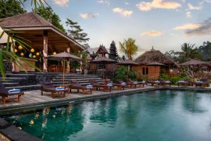 a pool at a resort with chairs and umbrellas at Cassowary Villas Sidemen by AGATA in Sidemen
