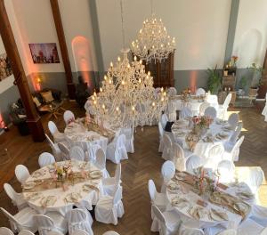 a room with white tables and white chairs and chandeliers at Wellenreiter in Tating