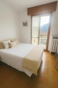 a white bed in a room with a large window at CASA STAVELLO in Sernio