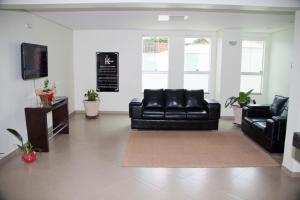 a living room with a black leather couch and a tv at HC Hotel Paraopeba in Paraopeba