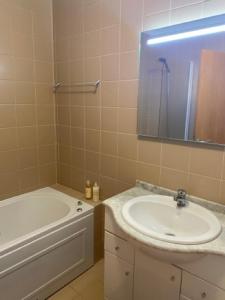 a bathroom with a sink and a tub and a mirror at Apart. Dunas da Torreira in Torreira +25 photos