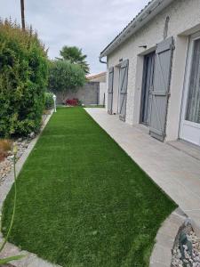 a yard with green grass next to a house at Au Coeur du Bocage Vendéen in Chantonnay