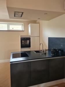 een keuken met een zwart aanrecht en een wastafel bij Tussen poort en toren in Sneek