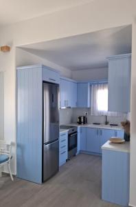 a kitchen with blue cabinets and a stainless steel refrigerator at Villa Manesi in Kithnos +14 photos