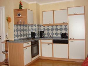 a kitchen with white cabinets and a black counter top at NEU Ferienwohnung Gudrun in Helmbrechts +1 photo