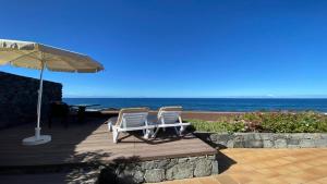 due sedie e un ombrellone su una terrazza con la spiaggia di Casa Blanca - Sunset Villa a Valle Gran Rey