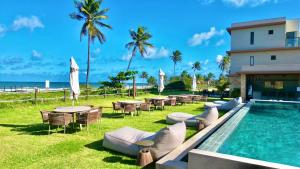 a resort with a swimming pool and tables and chairs at Apartamento Pé na Areia Cond Alphaville Guarajuba in Camaçari