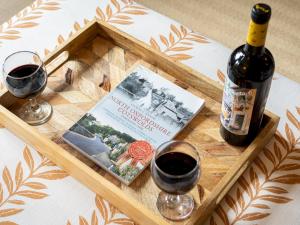 une bouteille de vin et un livre sur un plateau avec des verres à vin dans l'établissement Charming 2 Bed Cottage in the Heart of Adderbury Pass the Keys, à Adderbury