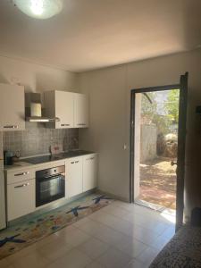 a kitchen with white cabinets and an open door at Blue Apartment in La Maddalena +9 photos