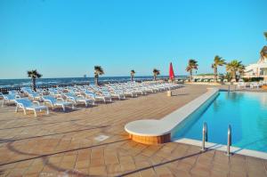 a row of white chairs next to a swimming pool at Blue Marine Village in Rodi Garganico