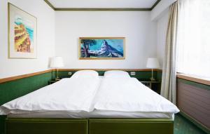 ein Schlafzimmer mit einem Bett mit weißer Bettwäsche und einem Fenster in der Unterkunft Hotel Arlette beim Hauptbahnhof in Zürich