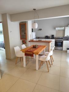 a kitchen with a wooden table and white chairs at Departamento Costa Ramayon in San Martín de los Andes