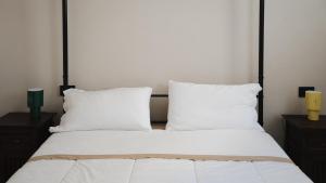 a bed with white sheets and pillows and two candles at Casa Cucunci in Modica