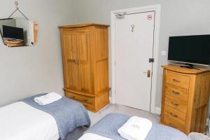 a bedroom with a bed and a tv and a dresser at Denecrest Guest House in Windermere