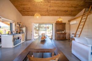 un soggiorno con tavolo in legno e una cucina di A Terra - Villa à 200m de la mer a Pianottoli-Caldarello