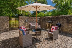 a table and chairs with an umbrella on a brick patio at Home Farm Byre in Tormarton