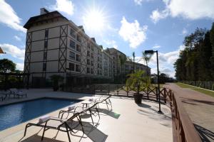 Vista Azul Apart - Vista Mata Atlântica في بيدرا أزول: مبنى به مسبح وكراسي بجوار مبنى