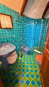 a blue tiled bathroom with a toilet and a sink at Villa Degli Artisti in Cugnana