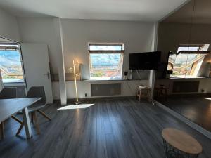 a living room with a table and two windows at Bel appartement Vue Mer Climatisé à Biarritz in Biarritz