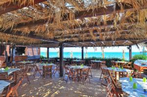 a restaurant with tables and chairs under a straw umbrella at Blue Marine Village in Rodi Garganico