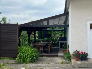 a pergola with a wooden table in a backyard at IDa House in Sveti Ivan Zelina