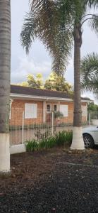 a house with a fence and two palm trees at Pousada Senda do Sol - Chácara Fornazari in Irati