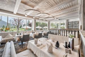 a restaurant with white tables and chairs and large windows at Natur & Spa Hotel Lärchenhof in Seefeld in Tirol