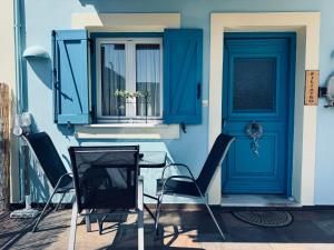 una casa con una porta blu, sedie e una televisione di Portolos Apartments - Filiatro a Vathi