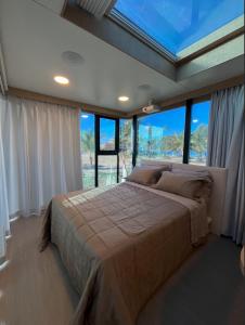 a bedroom with a large bed in a room with windows at Pousada Ilha Canela in Palmas