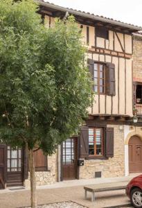 a tree in front of a building with a bench at Escapade lauragaise in Saint-Félix-Lauragais