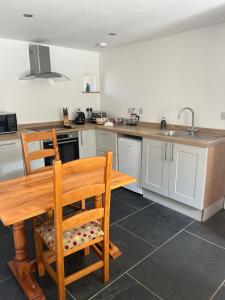 a kitchen with a wooden table and a wooden chair at Cornish Billys Barn in Penzance