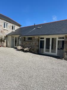 a stone house with two chairs in front of it at Cornish Billys Barn in Penzance