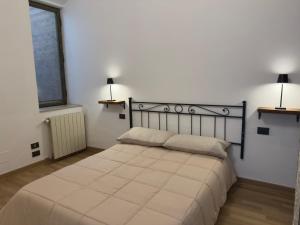 a bed in a room with two lamps on the wall at Tuscany Saloon - Historical centre in Colle Val D'Elsa
