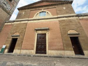 a church with a brown door and two windows at Tuscany Saloon - Historical centre in Colle Val D'Elsa +4 photos