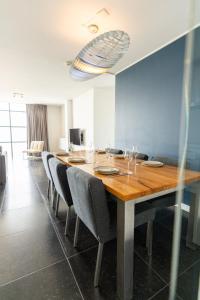 a dining room with a long wooden table and chairs at Poort Beach Boutique Apartments in Bloemendaal Aan Zee