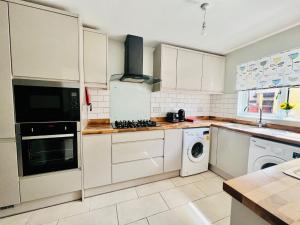 a kitchen with white cabinets and a washer and dryer at Spacious 6 Bedroom House with Free Parking for Contractors and Business in Basildon