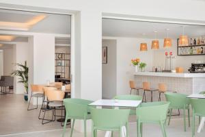 a dining room with green chairs and tables at Aparthotel Marina Drach in Porto Cristo