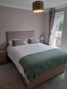 a bedroom with a large bed with a green blanket at Pullman Lodge in Glemsford