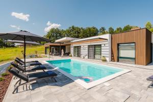 a house with a swimming pool with chairs and an umbrella at Villa Alma Nova in Laktaši