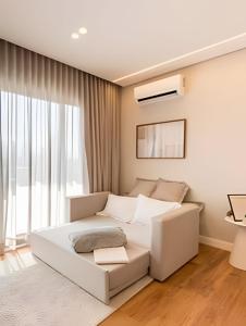 a bedroom with a white bed and a large window at Aconchegante Studio no Cambuí in Campinas