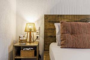 a bedroom with a bed and a table with a lamp at Wood in White in Panormos Skopelos