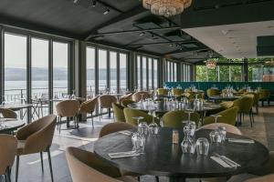 a restaurant with tables and chairs and windows at La Villa du Lac in Aiguebelette-le-Lac
