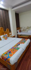 two beds in a hotel room with a colorful bedspread at Kochar con by guruji hospitality in New Delhi +7 photos