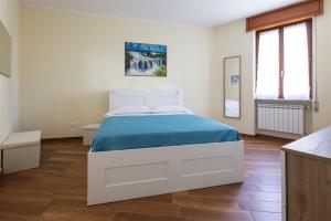a white bedroom with a bed with a blue blanket at IseoLakeRental - Fuori Porta in Tavernola Bergamasca