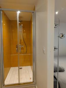 a shower with a glass door next to a bed at La myrtillette in Luchon +25 photos